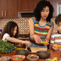 Hispanic mother and two kids making a meal in their kitchen.